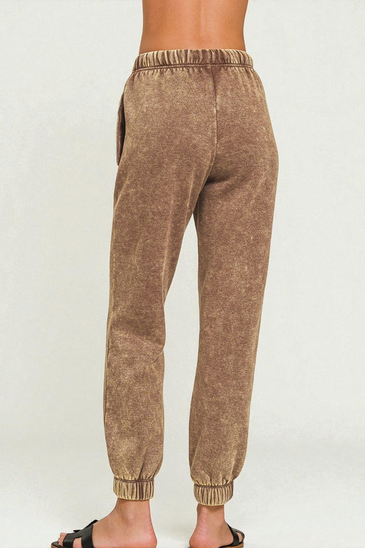 Brown jogger pants worn by a person on a white background