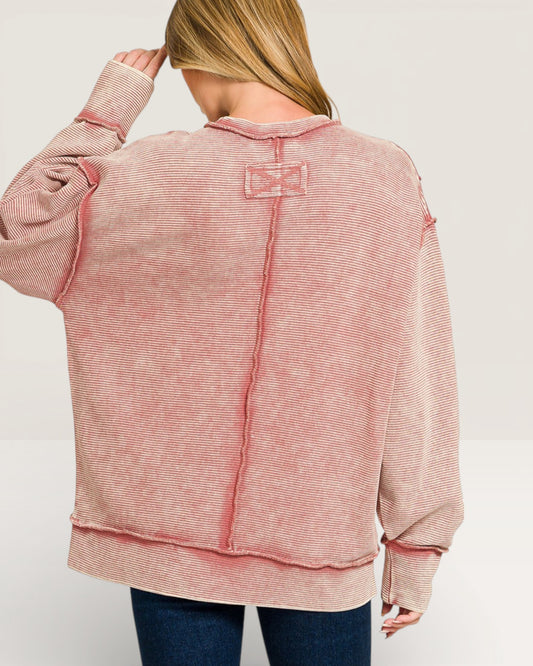 Pink textured sweater with a bow detail on a white background