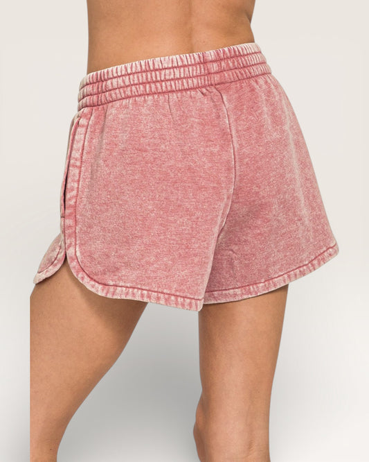 Pink shorts worn by a person on a plain background