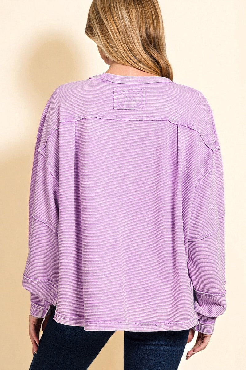 Person wearing a purple textured sweater on a beige background