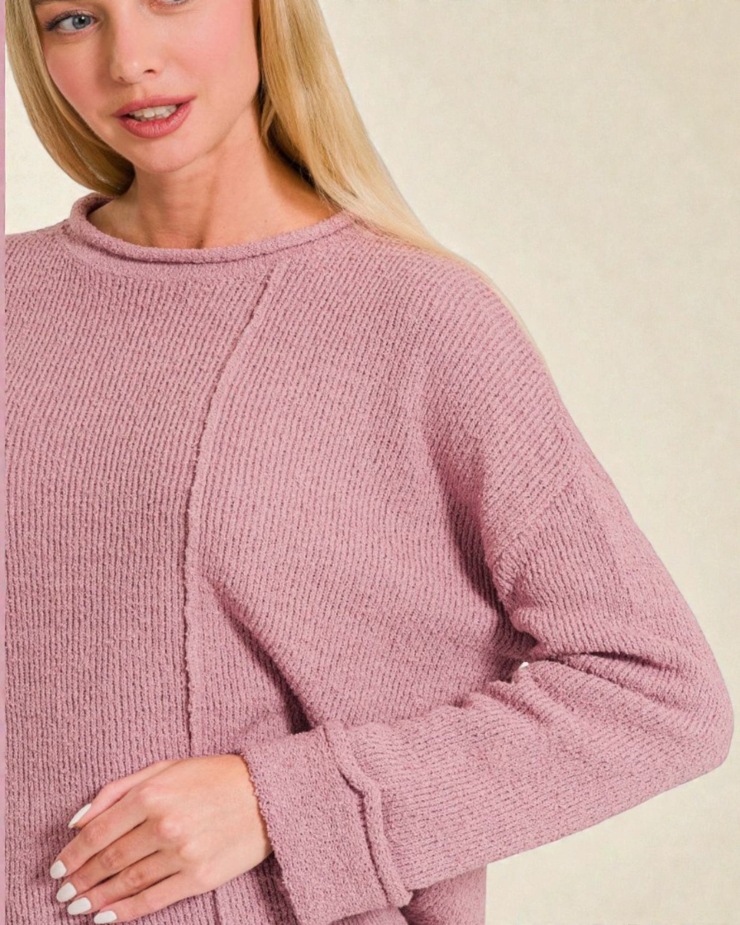 Person wearing a pink sweater on a plain background