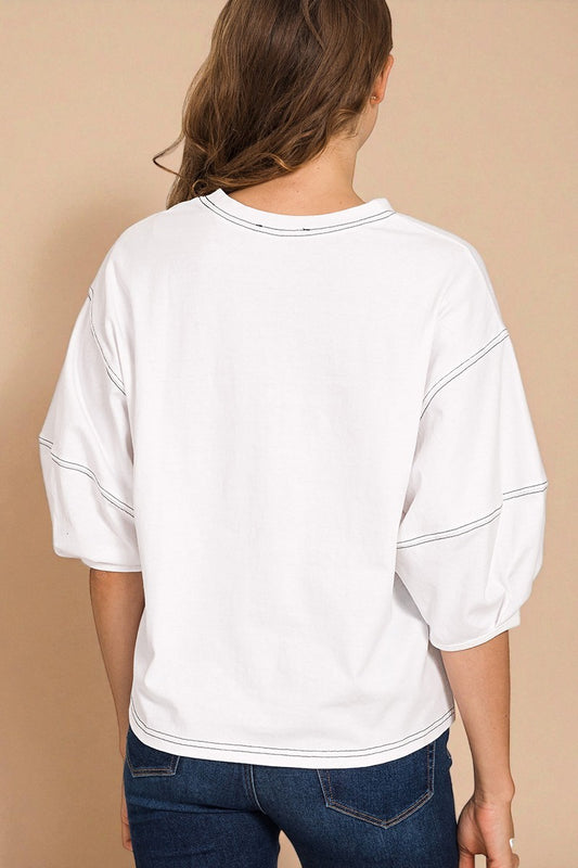 Person wearing a white oversized shirt with blue jeans on a beige background