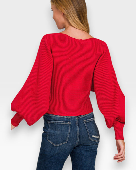 Person wearing a red sweater with balloon sleeves on a white background