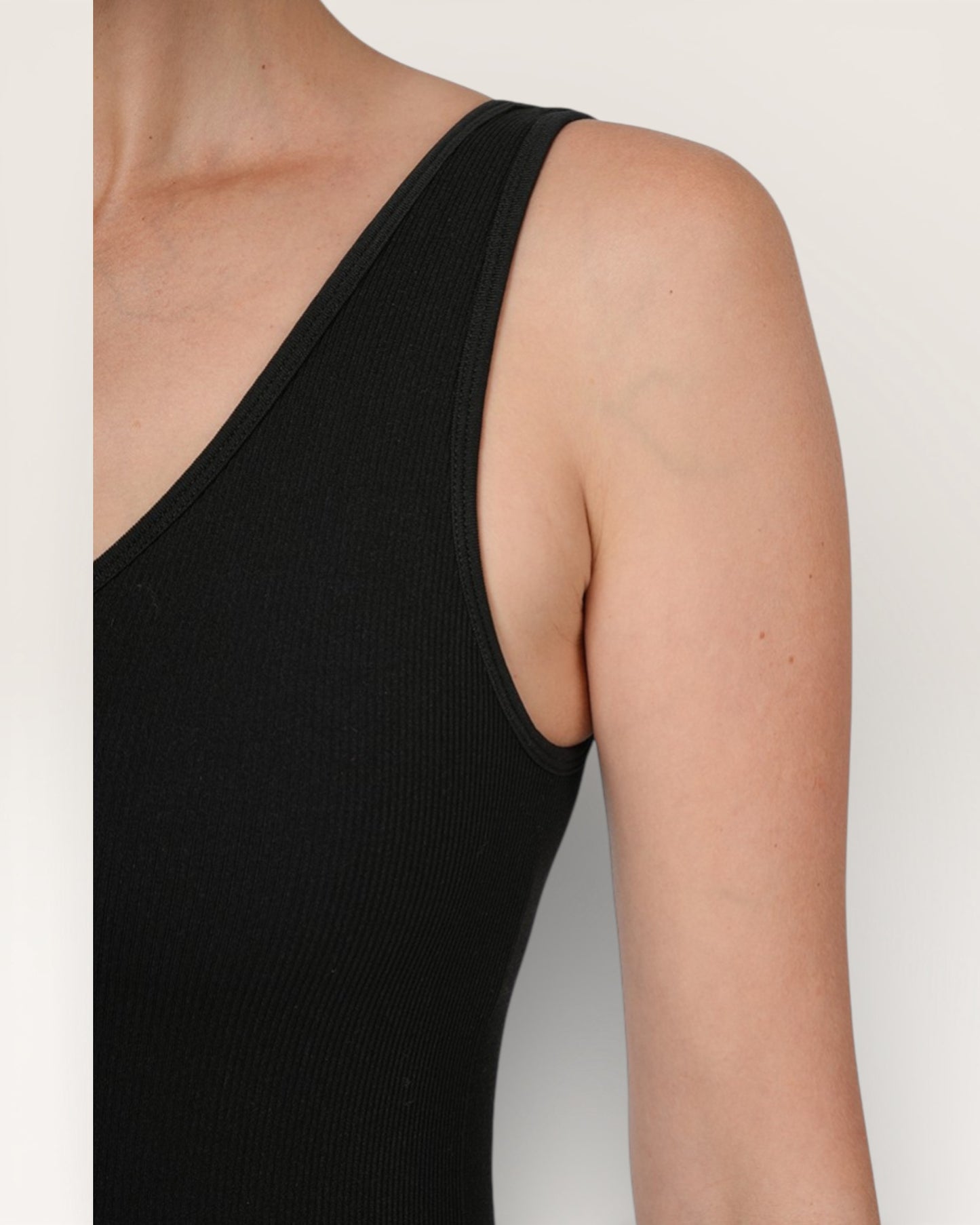 Black sleeveless top worn by a person on a plain background