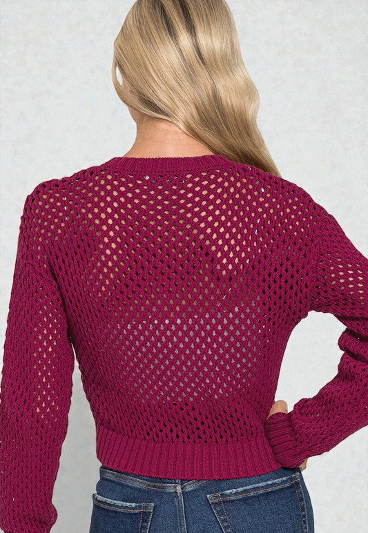 Person wearing a maroon open-knit sweater against a plain background