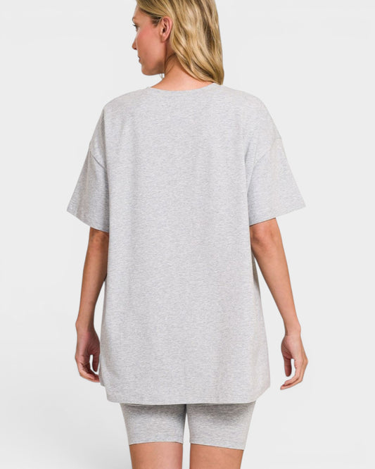 Person wearing a gray oversized t-shirt and shorts on a white background
