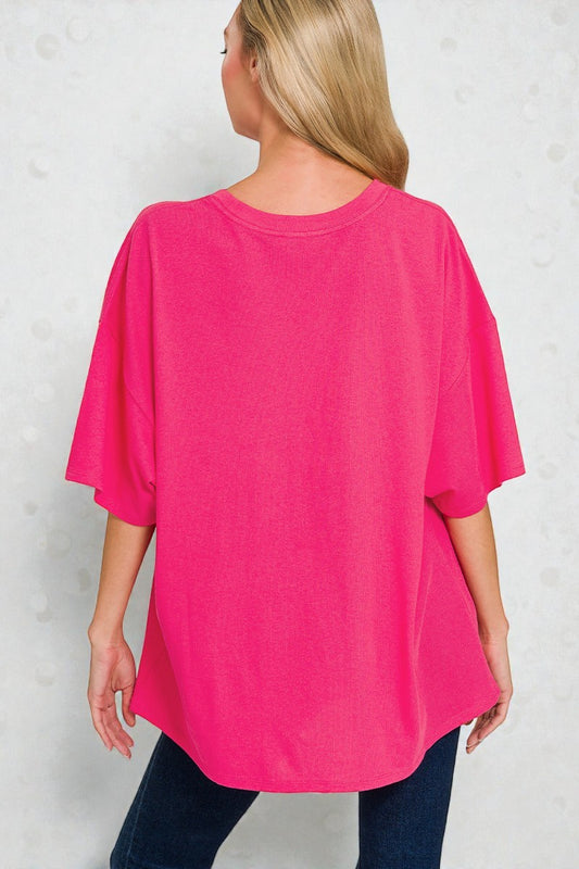 Person wearing a bright pink oversized t-shirt against a light gray background