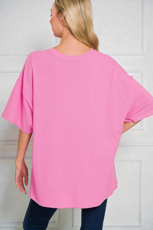 Person wearing a pink oversized t-shirt against a white background