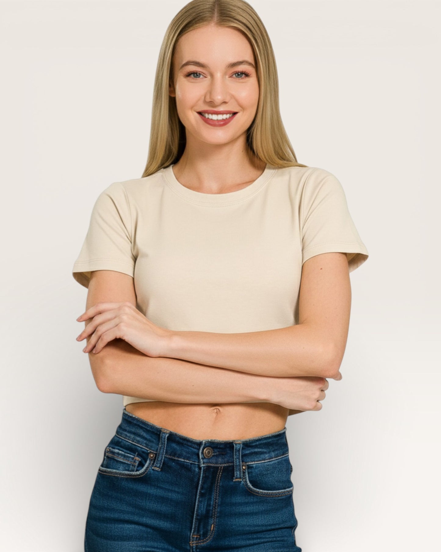 Woman wearing a beige t-shirt and blue jeans against a white background