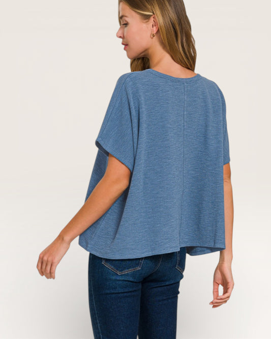 Woman wearing a blue oversized top and jeans on a white background