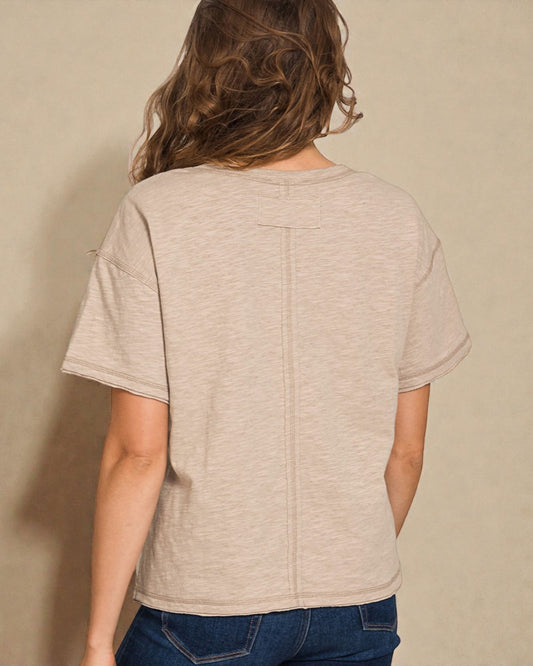 Person wearing a beige t-shirt against a beige background