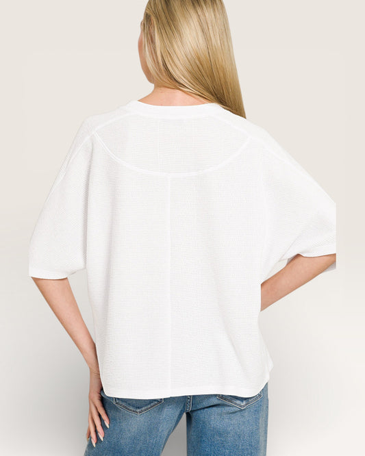 Person wearing a white t-shirt and blue jeans against a plain background