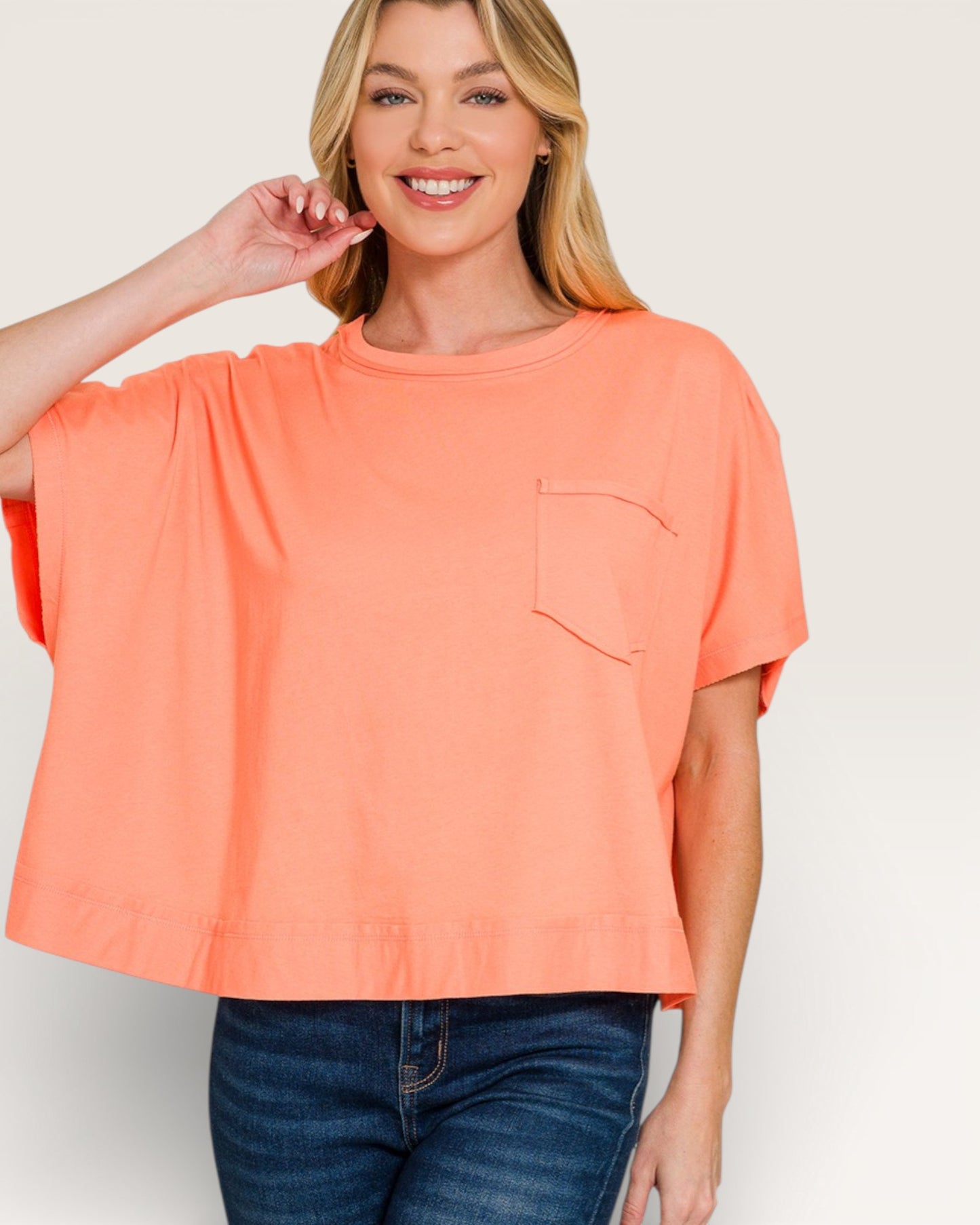 Woman wearing a coral oversized t-shirt with a pocket on a plain background