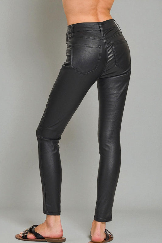 Black leather pants worn by a person on a gray background