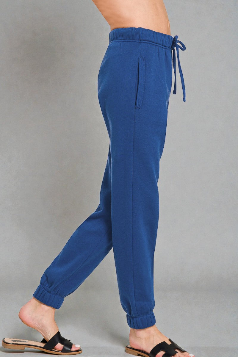 Blue sweatpants worn by a person on a gray background