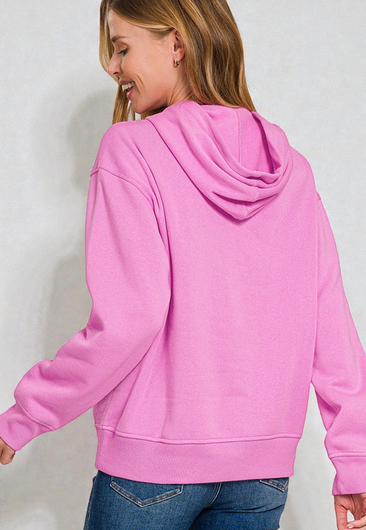 Person wearing a pink hoodie and blue jeans on a plain background