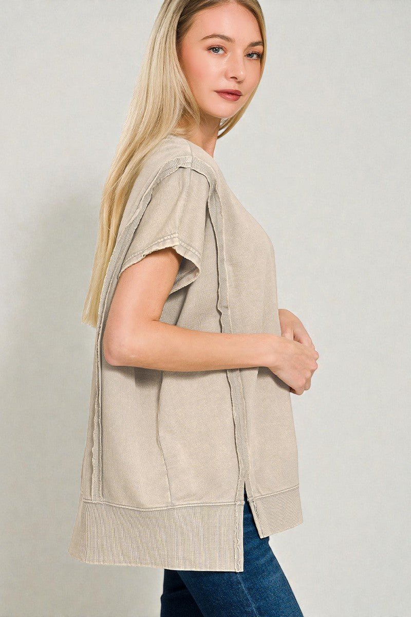 Woman wearing a beige sleeveless top with a plain background