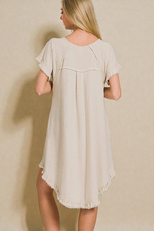 Woman wearing a beige dress against a plain background