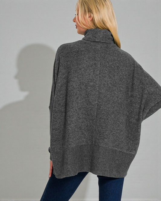 Person wearing a gray poncho against a plain background