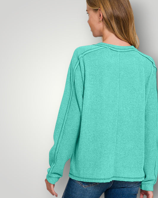 Person wearing a teal sweater against a plain background