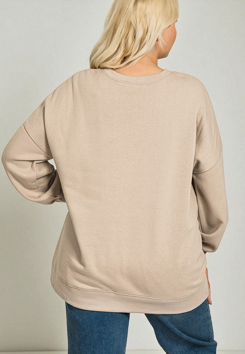 Person wearing a beige sweatshirt and blue jeans on a plain background