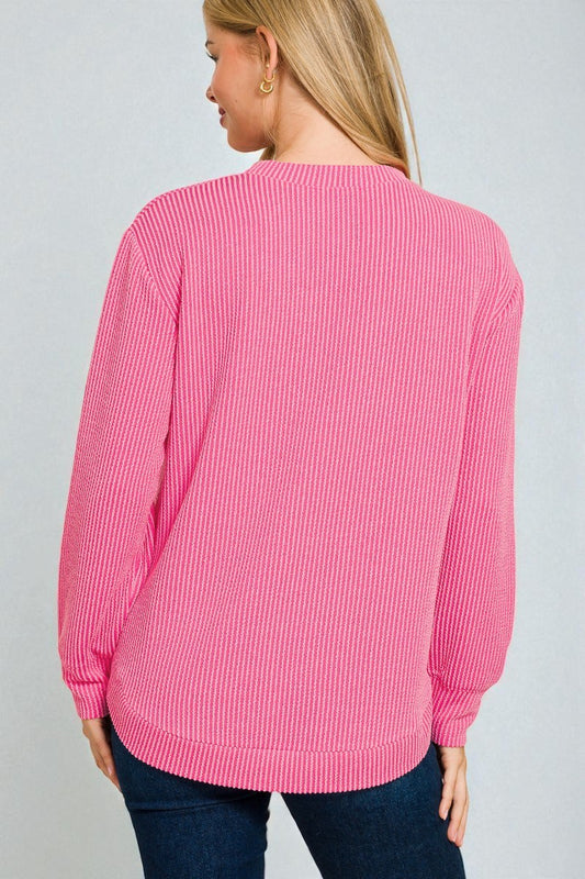 Person wearing a pink ribbed sweater on a gray background