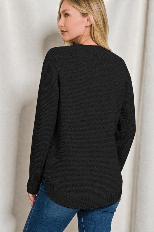 Woman wearing a black sweater and blue jeans against a white background