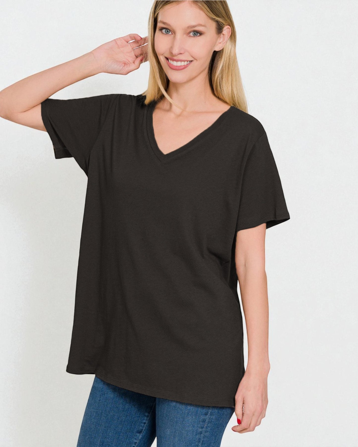 Woman wearing a black V-neck t-shirt and blue jeans on a white background