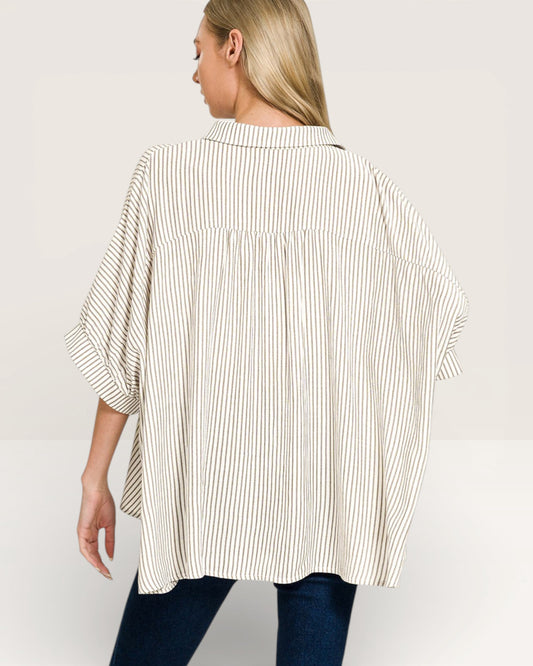 Woman wearing a loose-fitting, striped shirt on a plain background