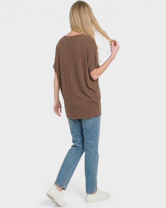 Person wearing a brown oversized shirt and blue jeans on a white background