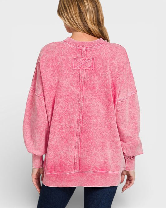 Pink acid-wash sweatshirt worn by a person on a white background