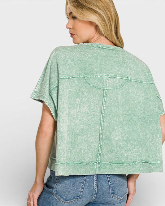 Woman wearing a green acid-wash shirt and blue jeans on a white background