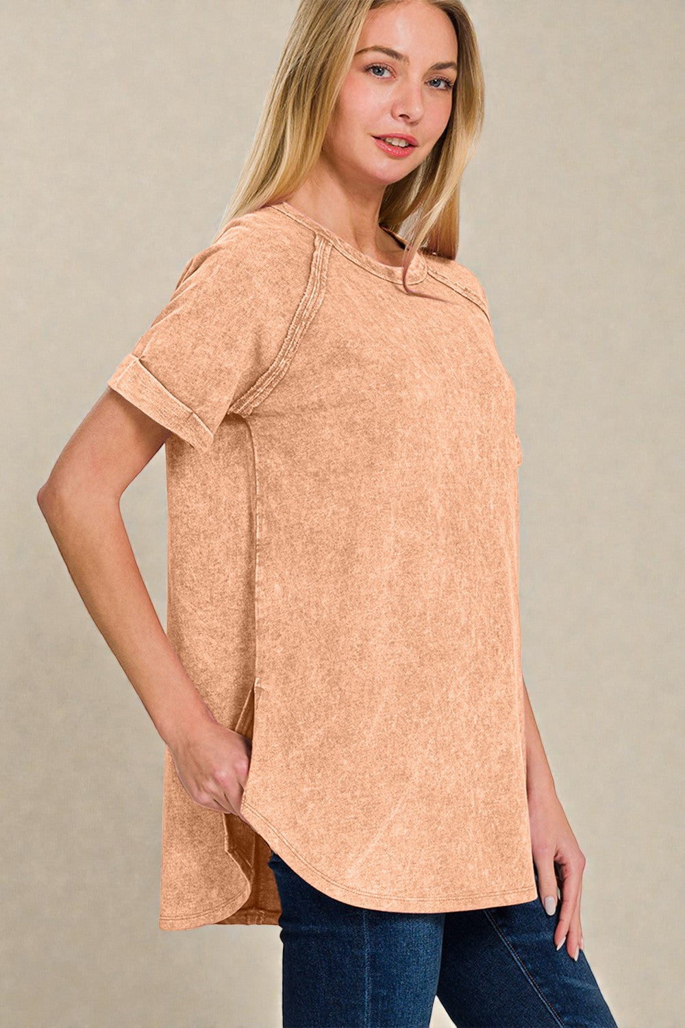 Woman wearing a tan short-sleeve top against a beige background