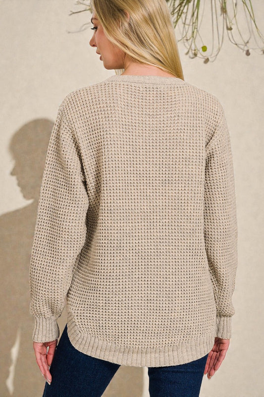 Woman wearing a beige knitted sweater against a neutral background