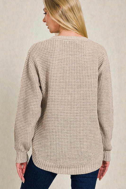 Beige knitted sweater worn by a person on a neutral background