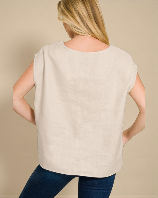 Woman wearing a beige sleeveless top against a beige background