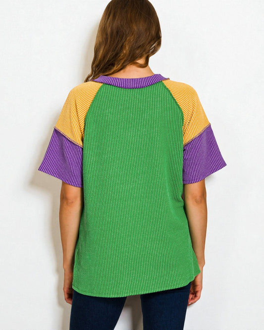 Person wearing a colorful shirt with green, yellow, and purple sleeves on a white background
