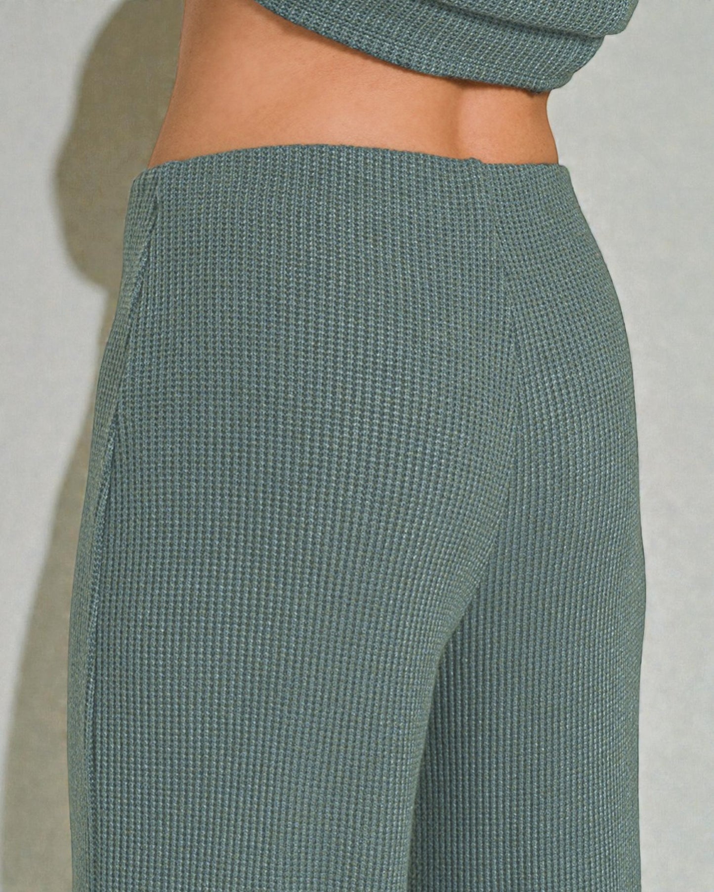 Teal ribbed pants on a plain background