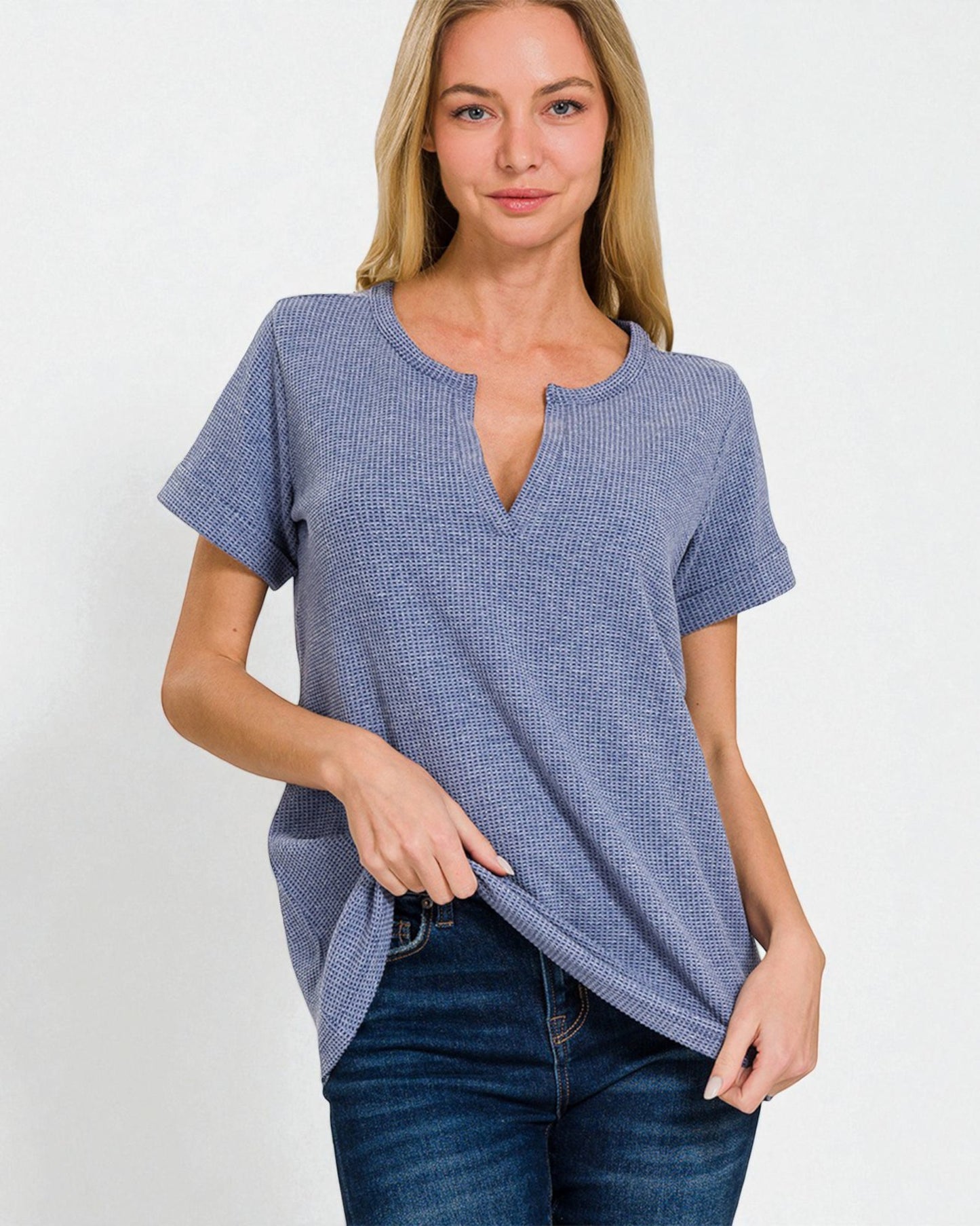 Woman wearing a blue textured top and jeans on a white background