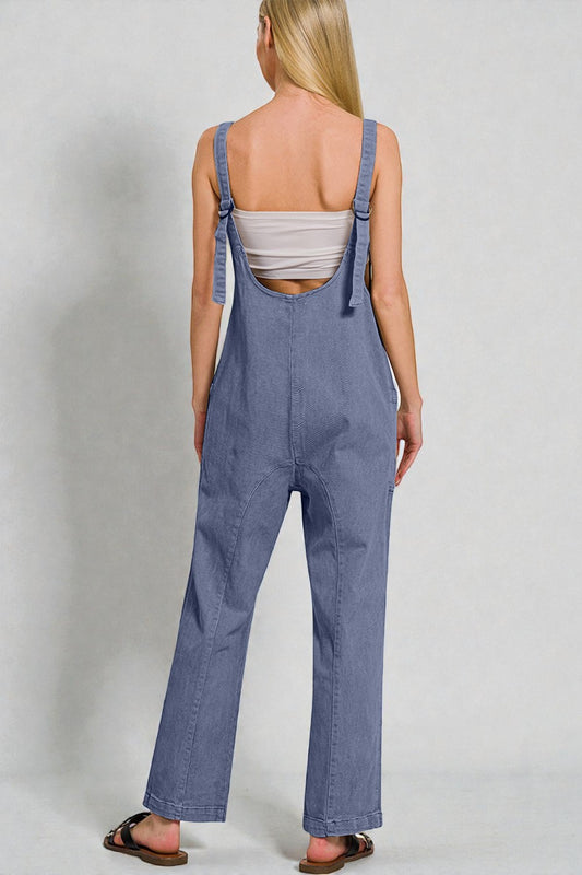 Person wearing blue denim overalls on a plain background