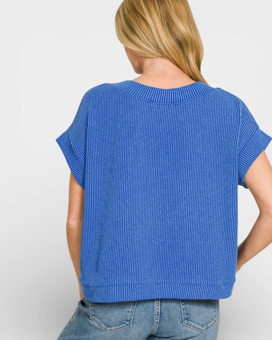 Person wearing a blue ribbed sweater on a white background