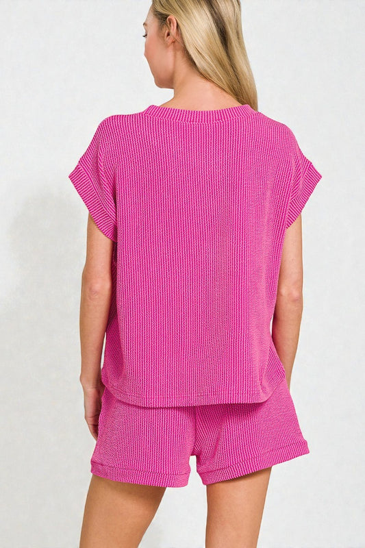 Woman wearing a pink textured top and shorts set on a white background