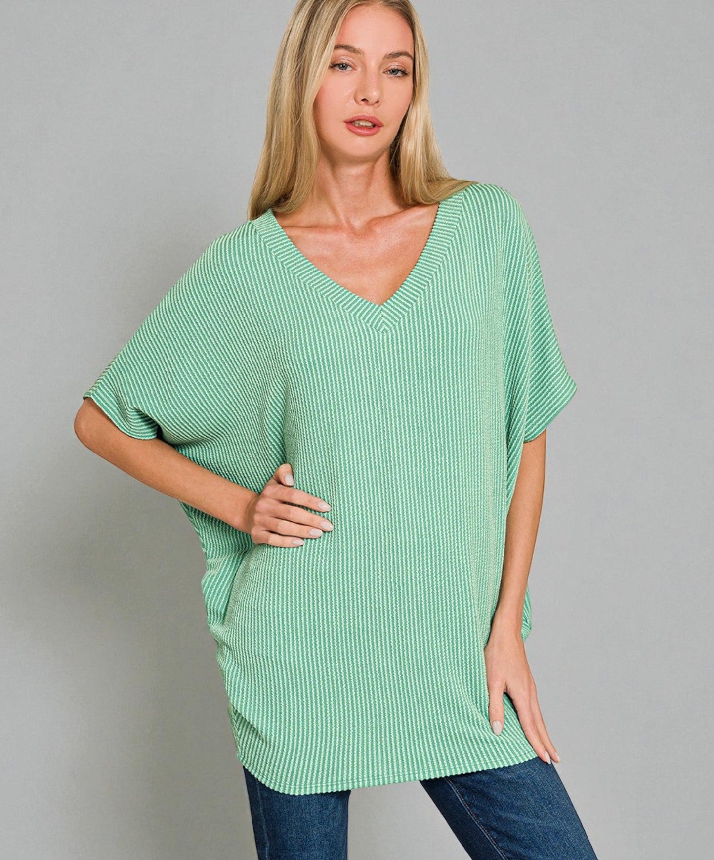 Woman wearing a green ribbed sweater against a gray background