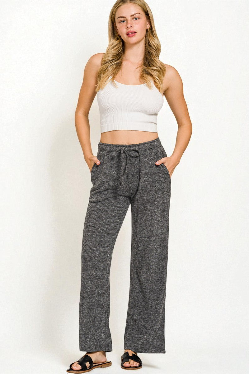 Woman wearing gray drawstring pants and a white top on a white background