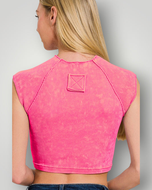 Person wearing a pink sleeveless top with a subtle pattern on a plain background