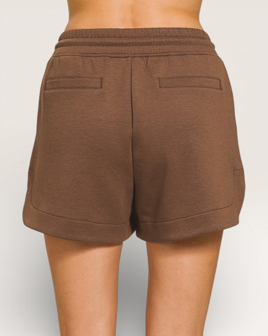 Brown shorts worn by a person on a plain background