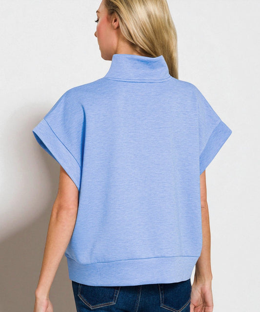 Woman wearing a blue short-sleeve shirt with a plain background