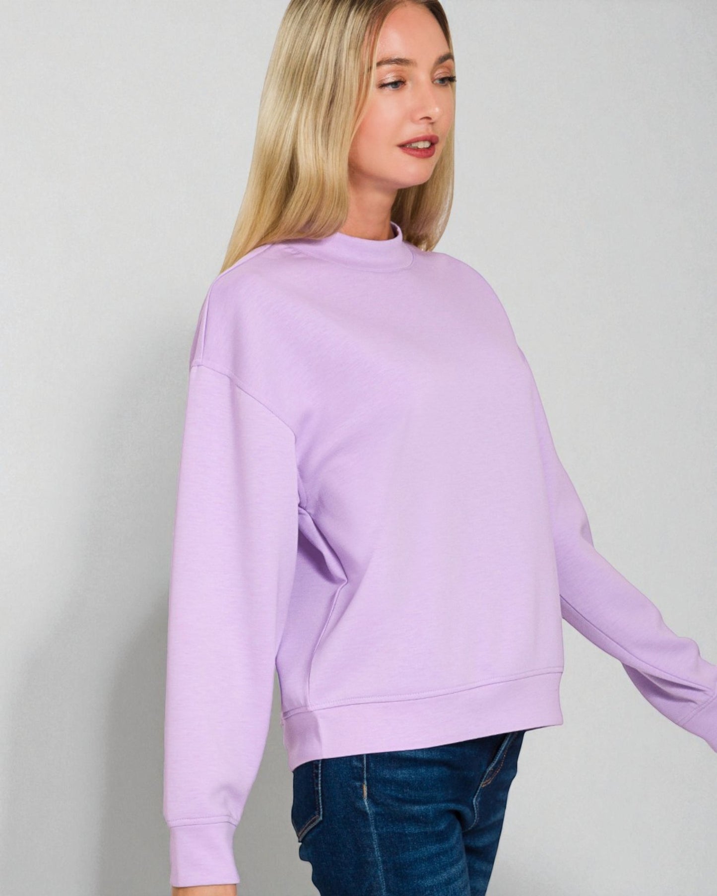 Woman wearing a light purple sweatshirt against a plain background