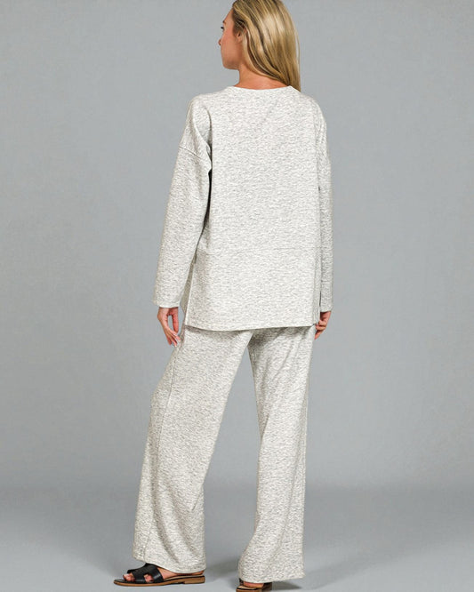 Woman wearing a light gray outfit with wide-leg pants on a plain background