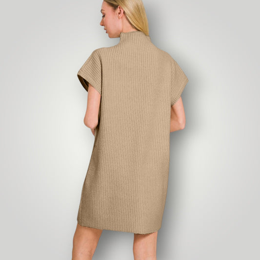 Woman wearing a beige ribbed dress against a plain background